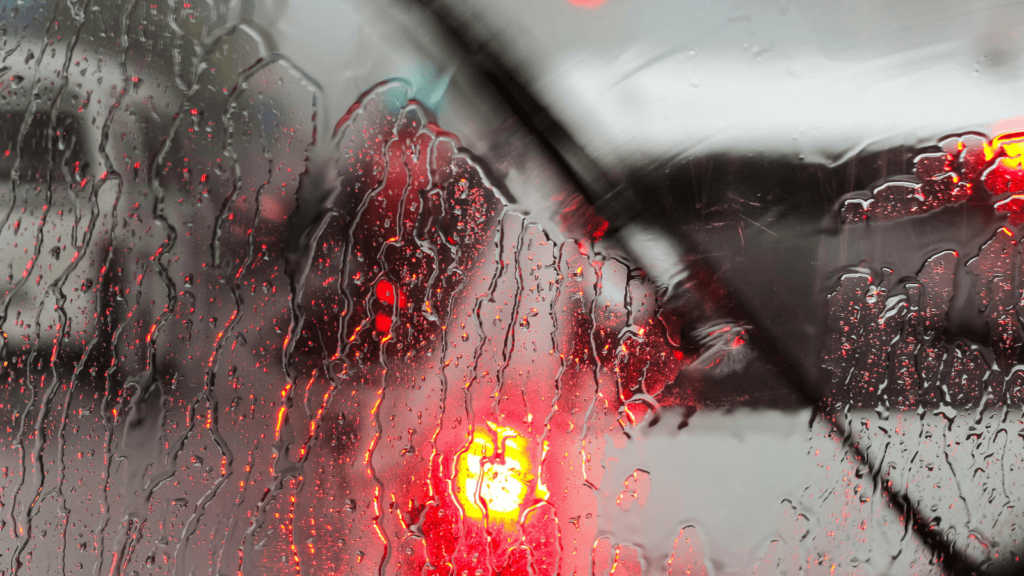 Tráfico en carretera visto a través de un parabrisas con gotas de lluvia.